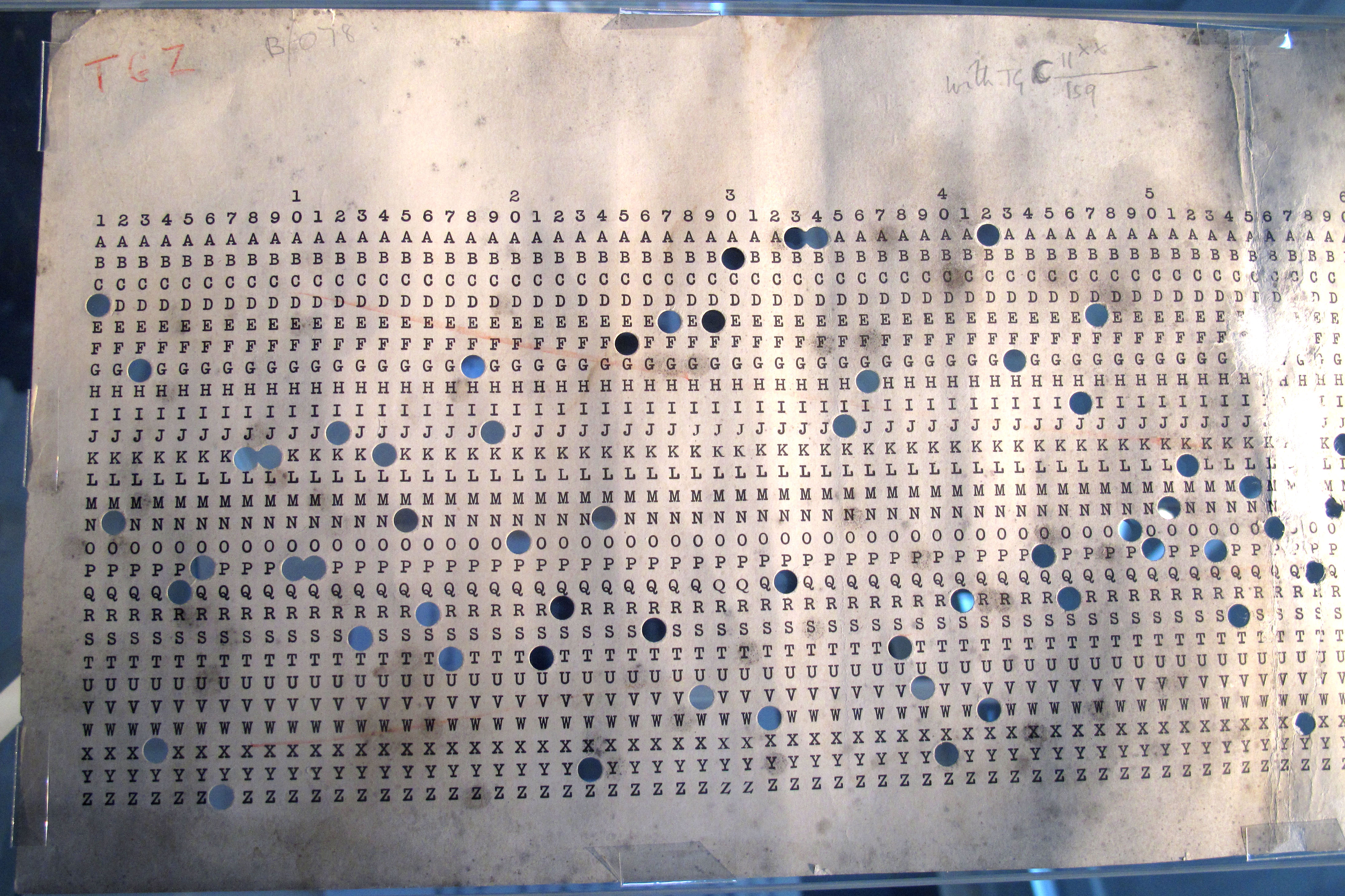 A surviving Banbury sheet with rows of letters A through Z and columns numbered across, holes punched at various positions